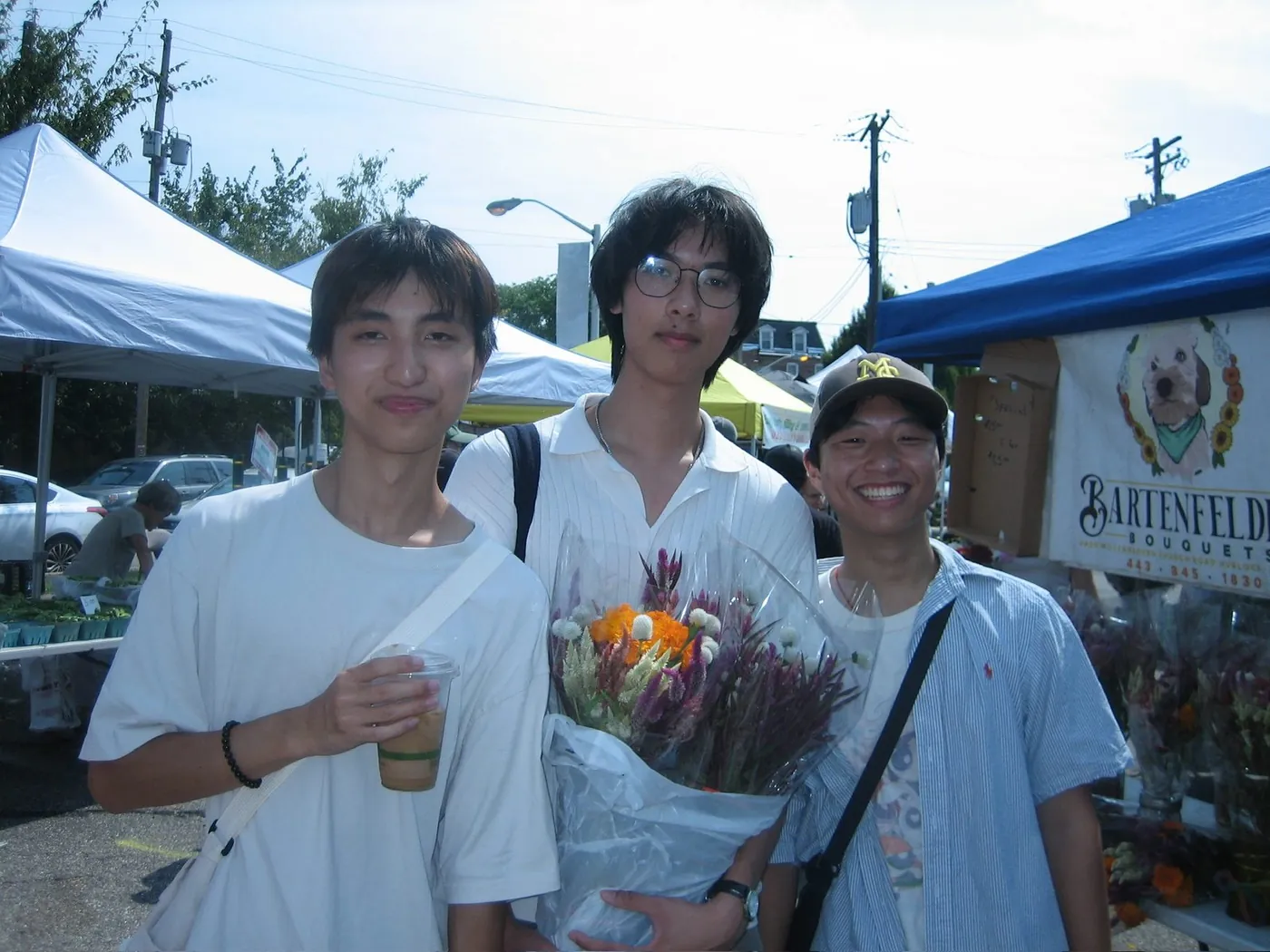 At an outdoor market, holding flowers