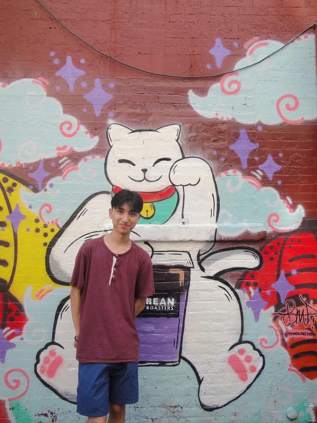 In front of a painted mural of a beckoning cat
