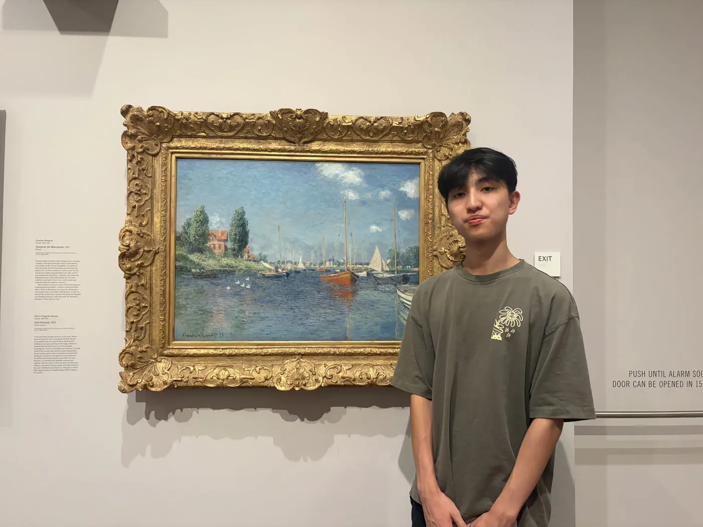 Beside a framed sailboat painting in a gallery