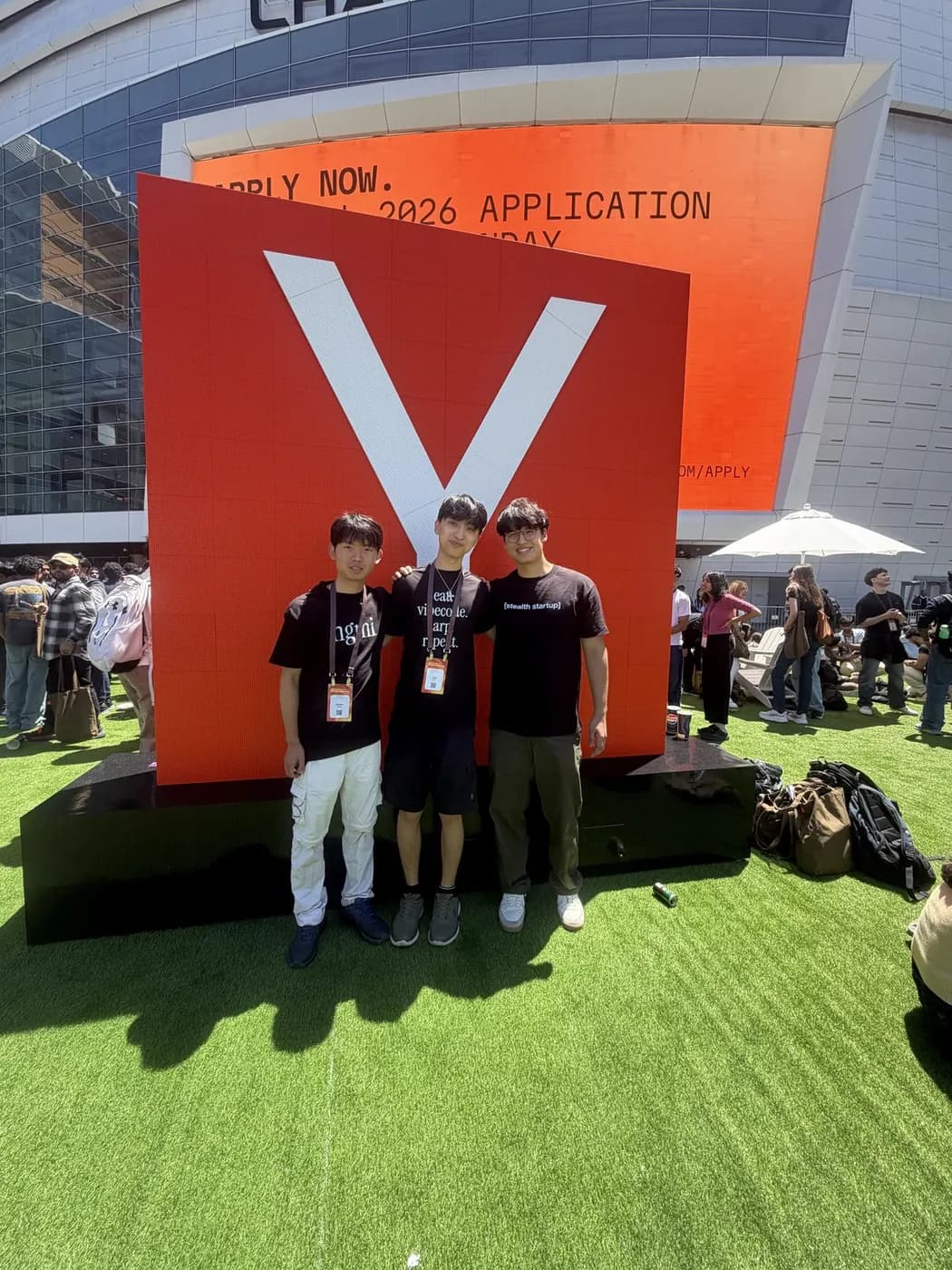 Three of us at an outdoor event beside a large red sign